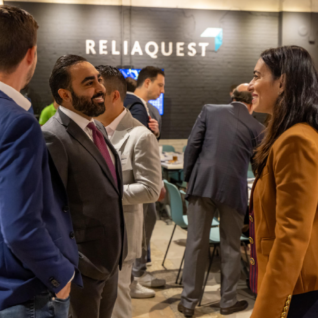 tgh ventures event photo featuring rachel feinman speaking with an event guest as more guests move around in the background in the ReliaQuest Auditorium at Embarc Collective